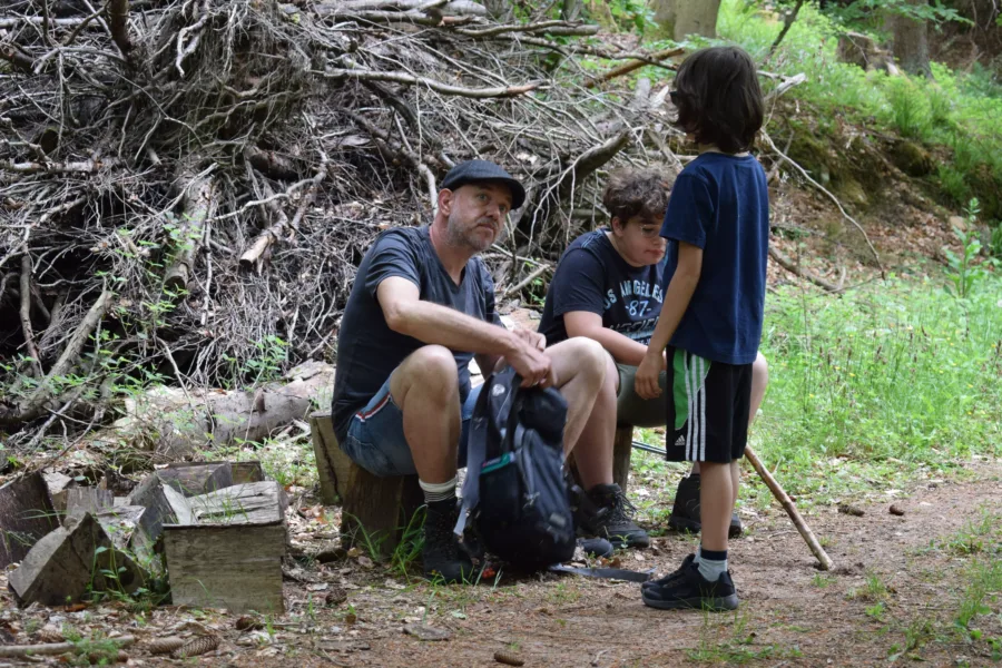 Familie rastet im Wald: Vater und zwei Kinder erholen sich von einer Wanderung.