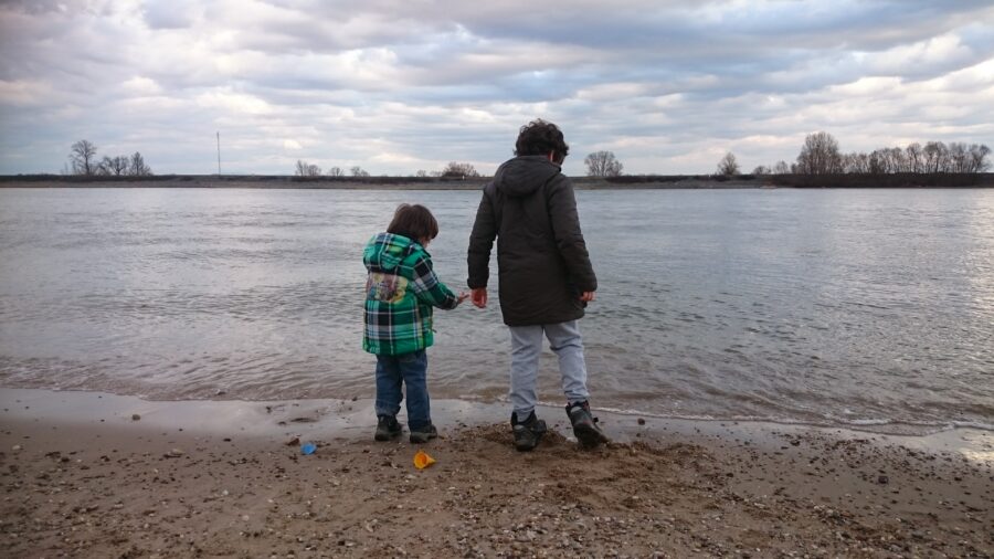 Zwei Kinder am Fluss schauen ins Wasser.